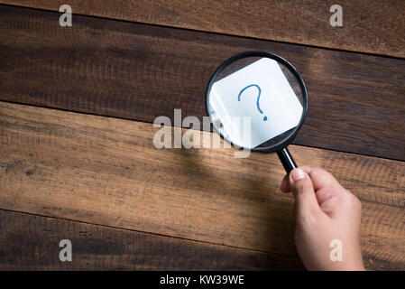 hand holding magnifying glass focusing on question mark. mystery and search concept Stock Photo