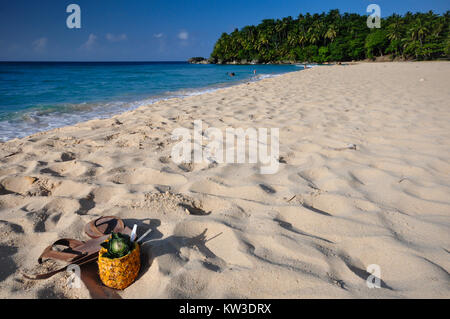 Pina Colada cocktail served in a fresh pineapple and  leather flip flops on Playa Grande, a quiet white sand beach in Cabrera, Dominican Republic. Stock Photo