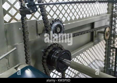 Triple strand roller chain going around three sprockets on industrial machine. the chain drive shaft Line Conveyor Industrial Stock Photo