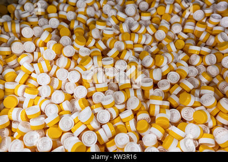 background of plastic bottle caps. plastic caps for bottles of yellow and white. The production process is a line for the packaging of plastic bottles Stock Photo