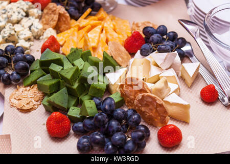 Different types of cheese cut into triangles lie on paper with strawberries. different types of cheese Stock Photo