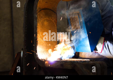 Welder with protective mask is working on metal welding Stock Photo