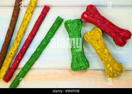 Pet food. Colorful chrunchy snacks in a shape of bones and sticks for dogs on a colored wooden background. Space for your text or image. Stock Photo