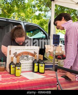 At a farmer's market in the San Francisco Bay Area town of Danville, California, a woman makes a purchase from a vendor for Frog Hollow Farm, an organic farm located in Brentwood, California, August 13, 2016. Stock Photo