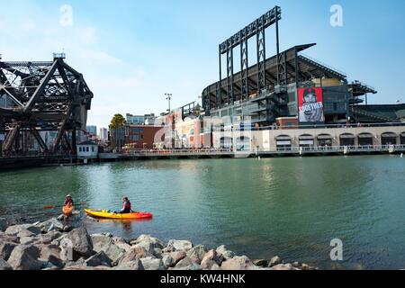 Two kaykers paddle through McCovey Cove near ATT Park, the baseball stadium of the San Francisco Giants, in the China Basin neighborhood of San Francisco, California, August 21, 2016. Boats often gather in the cove during home games in hopes of catching homerun balls which have been hit out of the ballpark and into the waters of the cove, San Francisco, California. Stock Photo