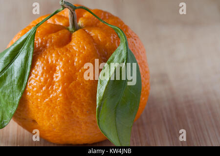 Single mandarin on wooden ledge, close up Stock Photo