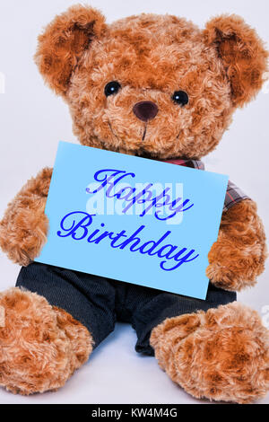 Cute teddy bear holding a blue sign that reads Happy Birthday isolated on a white background Stock Photo