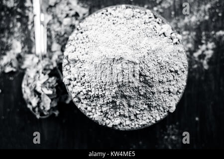 Raw organic powder of Henna,Lawsonia inermis in a clay bowl with its dry leaves on wooden surface. Stock Photo