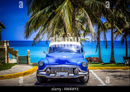 American blue Buick Eight classic car parked under palms on the beach in Varadero Cuba -Serie Cuba Reportage Stock Photo