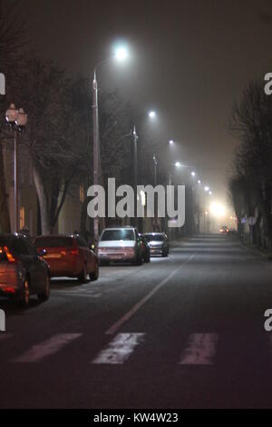 gray dark night city streets with bright shine lanterns in cold winter twilight Stock Photo