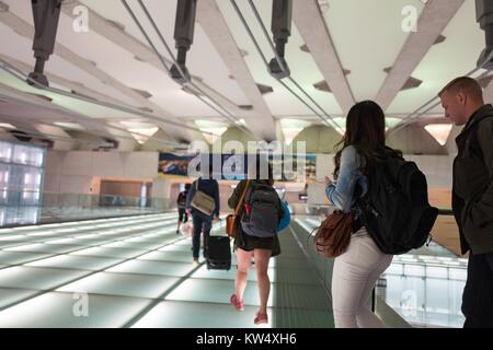 Travelers walk in a line across a lighted glass bridge at Dulles International Airport (IAD), Dulles, Virginia, September 24, 2016. Stock Photo