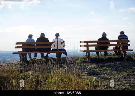 People seated on two benches on the edge of rock in Swabia, Germany Stock Photo