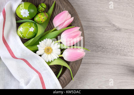 Easter wooden background with painted eggs and spring flowers on wooden plate, space for your text Stock Photo