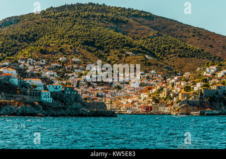 sailing through the Saronic sea and arrival at the port of the island of hydra with the buildings surrounding it down the mountain Stock Photo