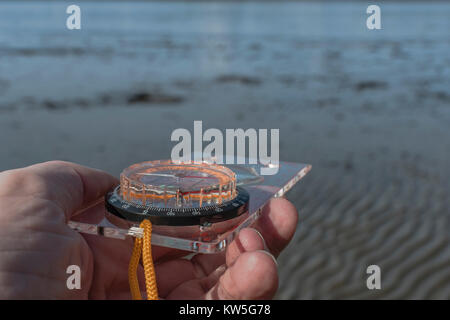 Orienteering compass in hand - for business 'direction', navigation, moral compass, getting your bearings, orienteering, coastal navigation. Stock Photo