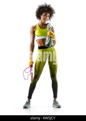 Fitness woman is sweaty. Photo of smiling african girl with skipping rope and towel in hands on white background. Resting time. Stock Photo