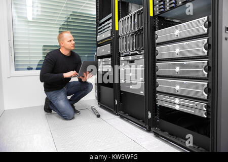 Consultant Using Laptop While Monitoring Servers In Datacenter Stock Photo