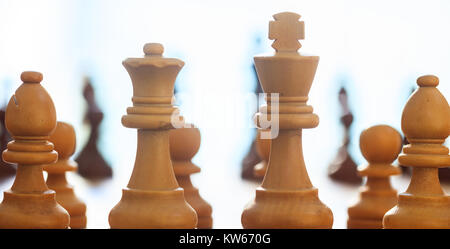 Chess pieces light brown. Close up view of king, queen, bishops, pawns with details, blur backdrop. Stock Photo