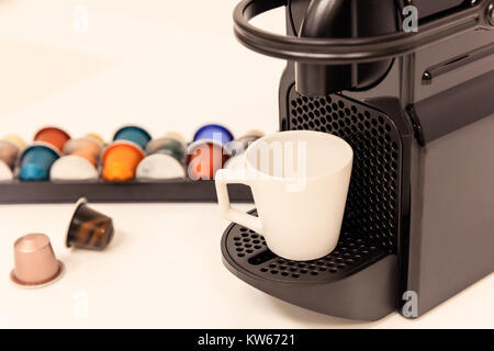 Espresso coffee maker machine in black color with capsules near it. Closeup, detail, blur backdrop. Stock Photo