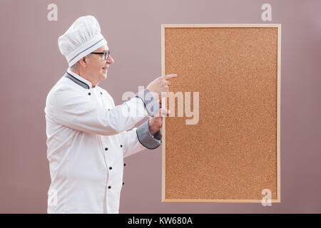 Portrait of restaurant's chef in working uniform showing what is on menu Stock Photo