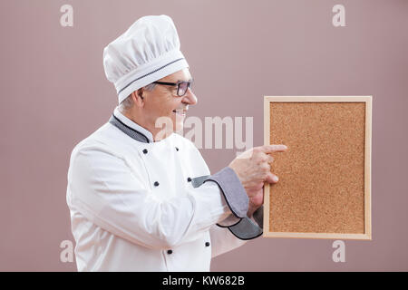 Portrait of restaurant's chef in working uniform showing what is on menu Stock Photo