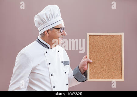 Portrait of restaurant's chef in working uniform showing what is on menu Stock Photo