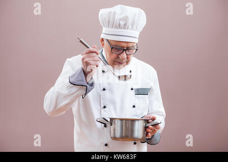 Portrait of restaurant's chef in working uniform tasting the meal Stock Photo