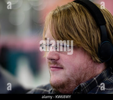 A man with glasses wearing headphones focussing in front of him Stock Photo