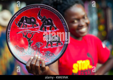 Stall proprietor holding hand-painted soapstone plate, Craft Centre, Entebbe, Wakiso, Uganda Stock Photo