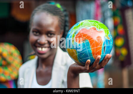 Stall proprietor holding hand-painted soapstone globe, Craft Centre, Entebbe, Wakiso, Uganda Stock Photo