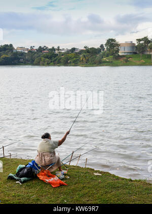 Belo Horizonte - Dec 26, 2017: Afro-Brazilian woman fish on Pampulha lake, despite the pollution, in Belo Horizonte, Minas Gerais, Brazil Stock Photo