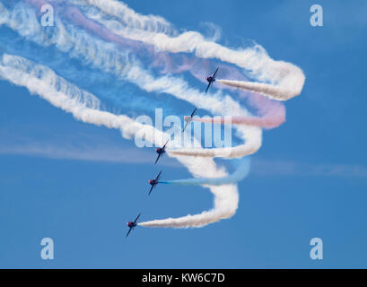 Five of the world famous Royal Air Force Red Arrows aeronautical display team carrying out a tight turn with vapour trails against a clear blue sky Stock Photo