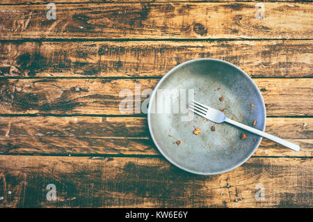 Top view or flat lay picture of a dirty plate after having eaten the dish on a grungy wooden table. Food concept. Stock Photo