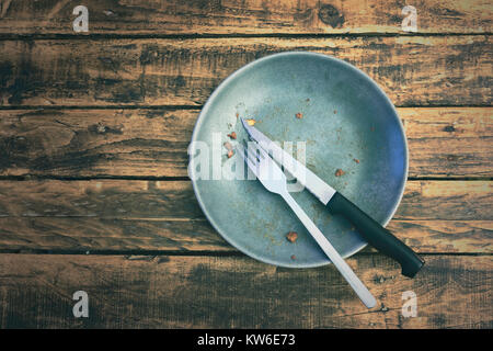 Top view or flat lay picture of a dirty plate after having eaten the dish on a grungy wooden table. Food concept. Stock Photo