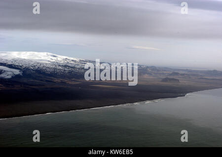 The snow-covered summit of the Myrdalsjokull  Glacier icecap, an active volcano, called, Katia, and the vast volcanic black ash beach on the south coa Stock Photo