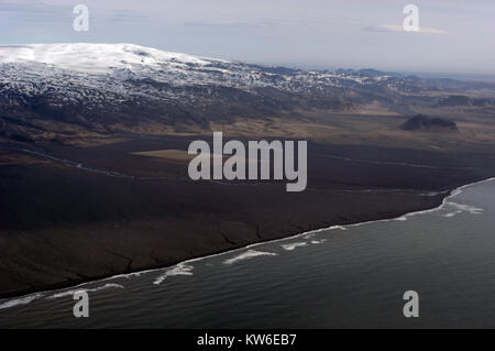 The snow-covered summit of the Myrdalsjokull  Glacier icecap, an active volcano, called, Katia, and the vast volcanic black ash beach on the south coa Stock Photo