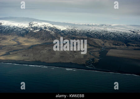 The snow-covered summit of the Myrdalsjokull  Glacier icecap, an active volcano, called, Katia, and the vast volcanic black ash beach on the south coa Stock Photo