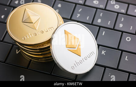 Digital currency physical Ethereum coins on black computer keyboard Stock Photo