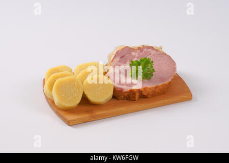 smoked pork neck with potato dumplings and sauerkraut on wooden cutting board Stock Photo