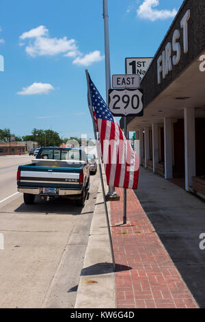 Giddings, Texas - June 13, 2014: Stret scene in the city of Giddings along the Highway 290 with a parked pickup truck and the American Flag in Texas,  Stock Photo