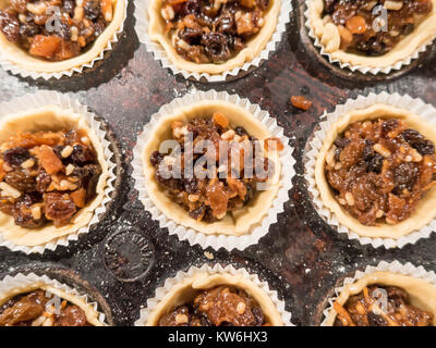Making Mince Pies: Mince pies in a baking tray. Circles of pasty have been pushed into the baking tin and filled with mincemeat. Close up. 13 of 16 Stock Photo