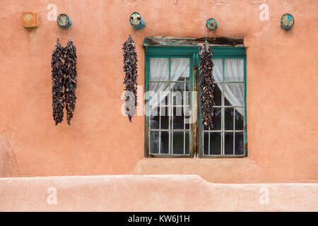 Red chili pepper ristras hanging on adobe buildings, Taos, New Mexico Stock Photo