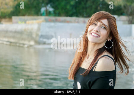 Portrait of a woman smiling, cheerful, beach at winter, outdoors, with long hair disheveled. Stock Photo