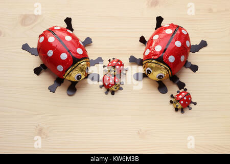 family of chocolate ladybugs with three kids on bright wood Stock Photo