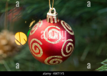 A closeup of a single red bauble decoration hanging from a Christmas tree Stock Photo