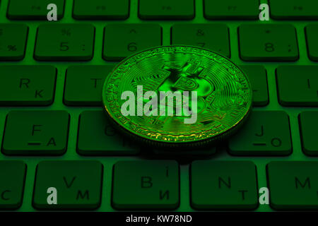 Gold Plated Iron Bitcoin on laptop keyboard with green neon light ...