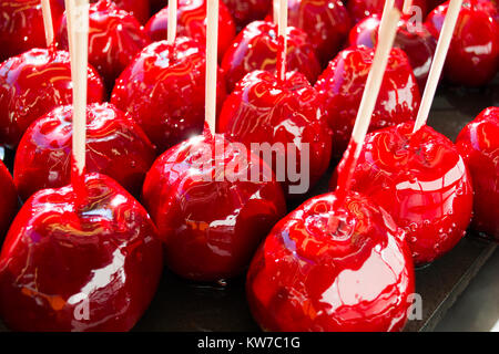 sweet glazed red toffee candy apples on sticks for sale on farmer market or country fair Stock Photo