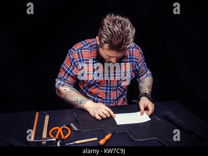 Leather cutter cutting out leather goods in his workplace Stock Photo
