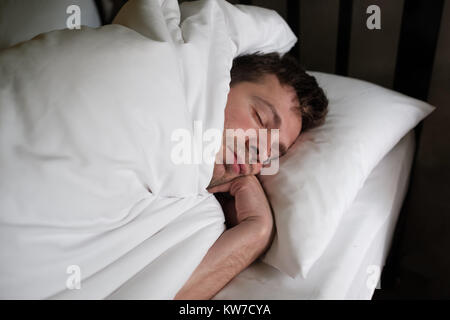 Caucasian man sleeping or napping in white bed Stock Photo