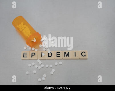 Epidemic spelled with tile letters in a row with an open bottle of oxycodone pills. Photographed from above on a stainless steel background. Stock Photo